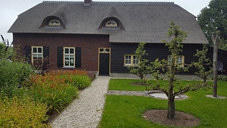 De rieten boerderij van Hoeve Strobol met tuinpad en fruitbomen