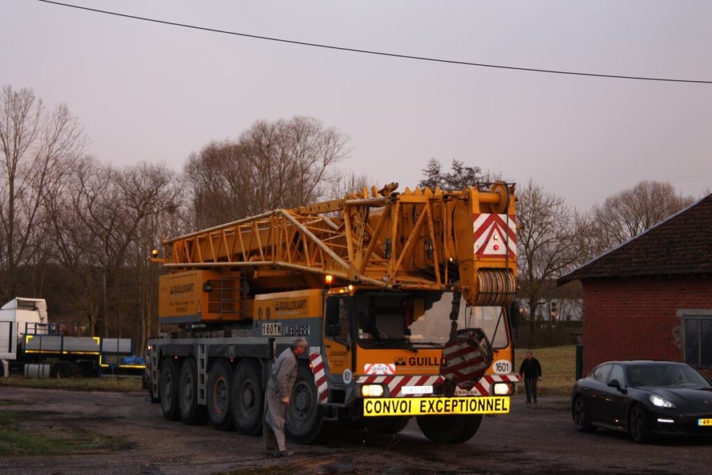 Een grote kraanwagen staat klaar om de stoommachine te takelen